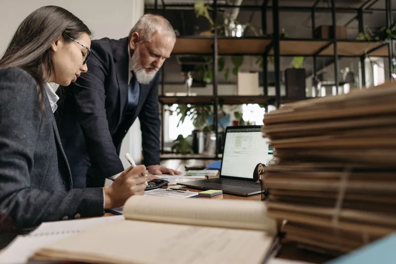 Two colleagues reviewing work together at a shared desk